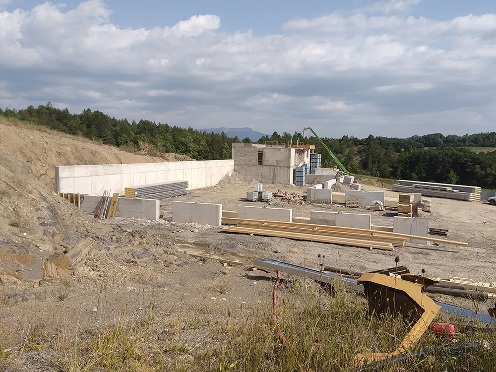 Mur de soutènement en béton armé et murs du hangar montés sur le chantier terminé à Upaix