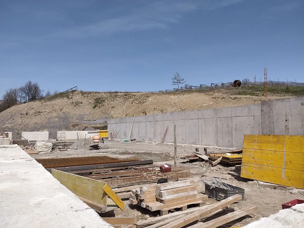 Mur de soutènement en béton armé décoffré contre le talus, banches et bétonnière à Upaix