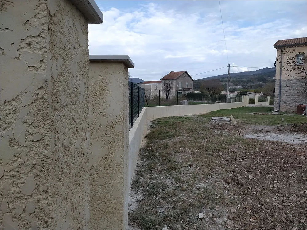Détail de l'enduit tyrolienne finition écrasée, sable de Mornas et chaux, sur un pilier à Sisteron