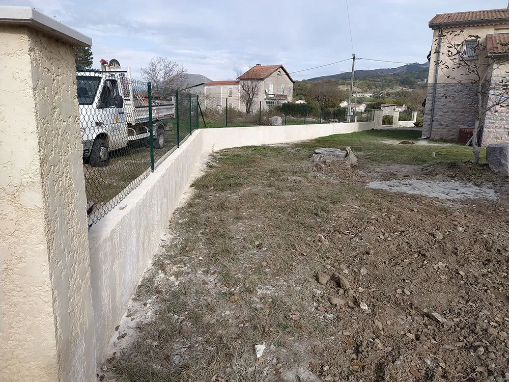 Mur de clôture enduit et grillage le long de la propriété à Sisteron