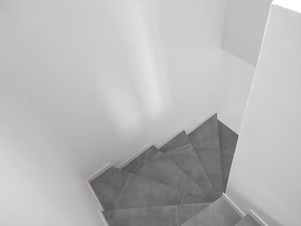 Escalier en béton habillé de carrelage anthracite effet béton dans une villa RE2020 à Château-Arnoux