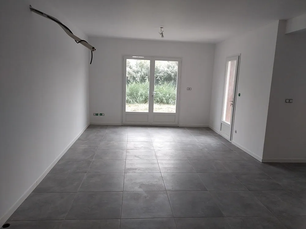 Séjour lumineux avec baie vitrée et carrelage grand format, villa RE2020 à Château-Arnoux